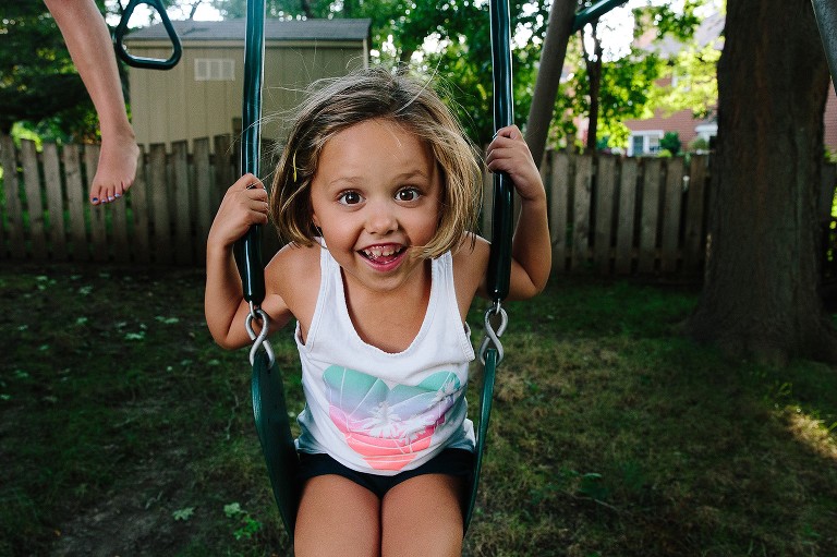 Big smile on girl riding on backyard swing 