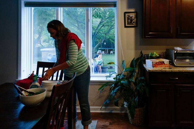 Mom sets down plates while daughter in the background is cleaning up. 
