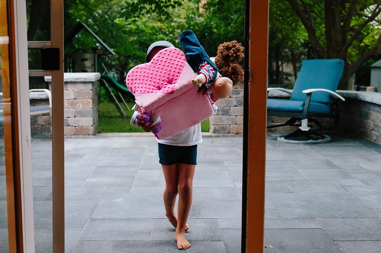 5 year old carries all her toys back inside from the porch 