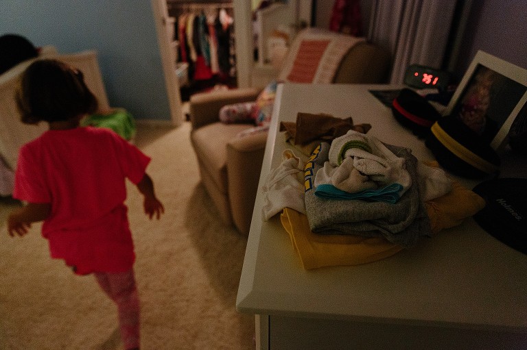 Girl walks by clothes that are laid out for next day.