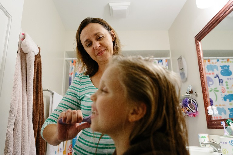 Mom smiles at daughter while brushing her hair after a shower.