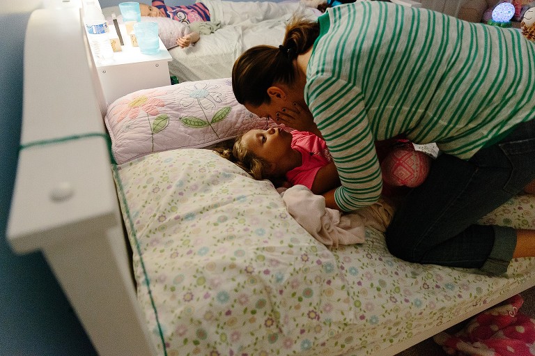 mom kisses 5 year old girl good night. 