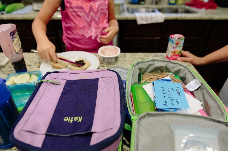 Daughter makes her lunch and mom packs lunchboxes 