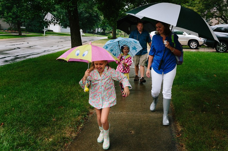 Family walks to school in the rain. 