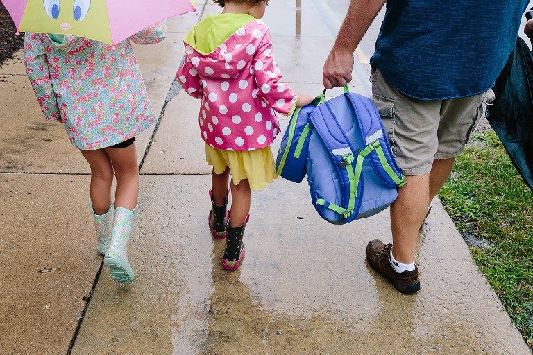 Dad holds all the backpacks and lunchboxes, 