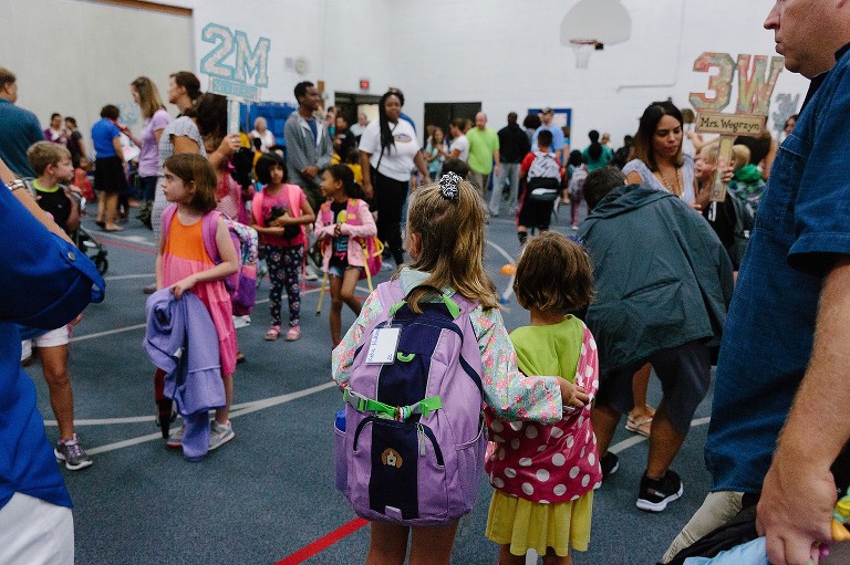Big sister guides little sister through crowded school space 