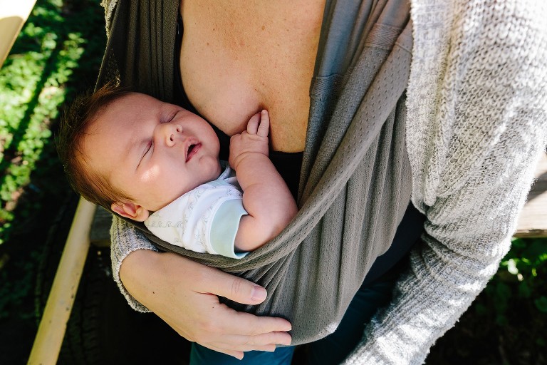 Top down view of sleeping baby in mother's arms at park 