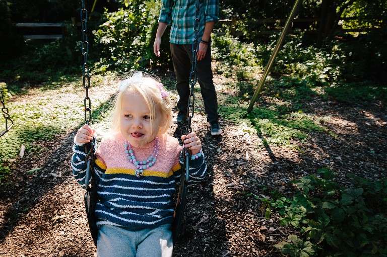 Girl swings on swings and make a "taco" tongue. 
