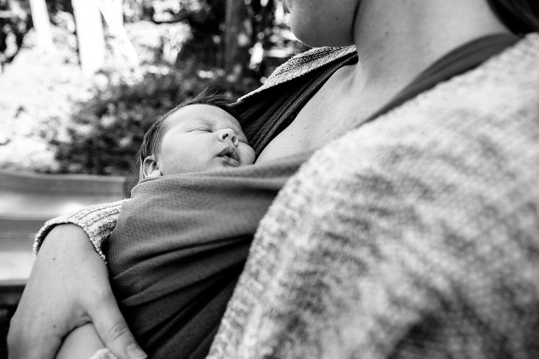 Mom bab-wears sleeping baby at the park 