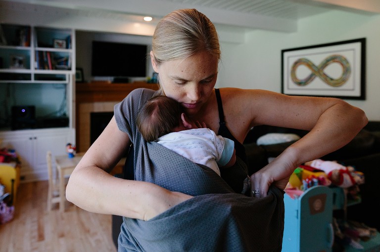 Mom wraps baby into cloth baby-wearing fabric. 