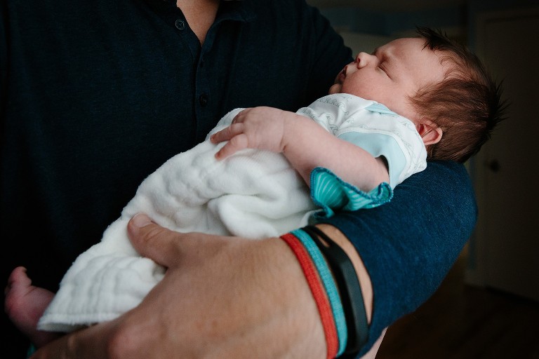 Dad holds newborn son in his arms 