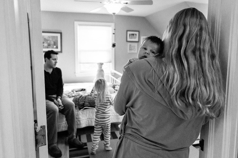 Mom and baby stand at the door while dad and daughter in bedroom choosing clothes for the day. 