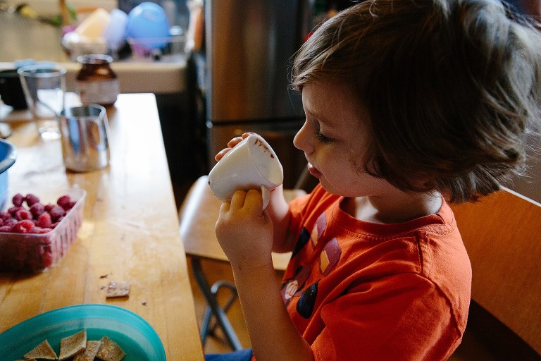 Boy looks into white mug for more "milk steamer" 