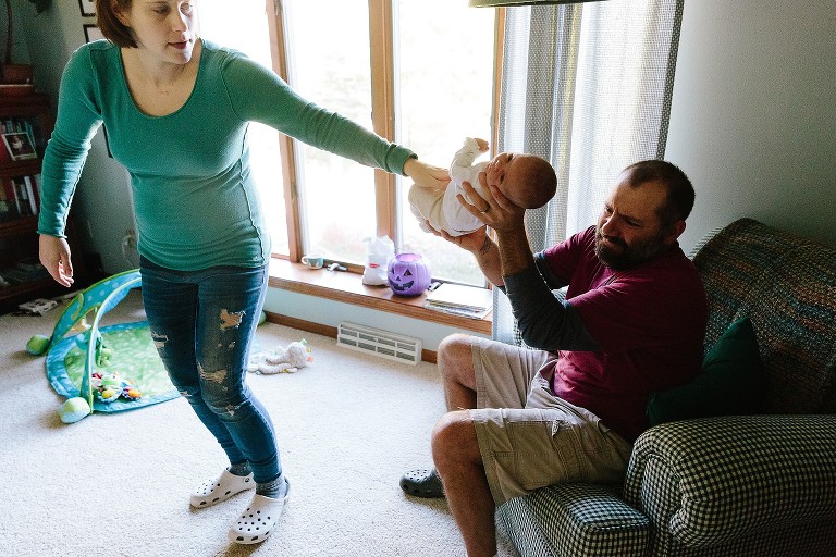 moms hands off newborn baby to dad to hold, four