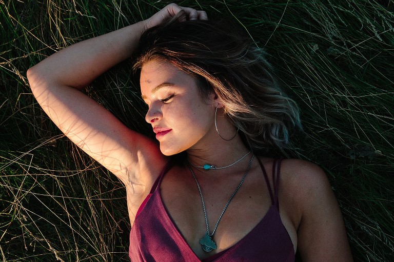 Young woman laying in grass at sunset