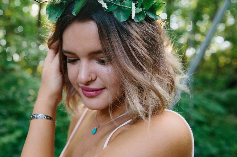 young woman gazes at the ground in forest.