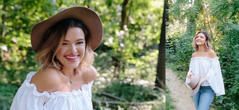 Young woman wearing hat smiles for camera in forest.
