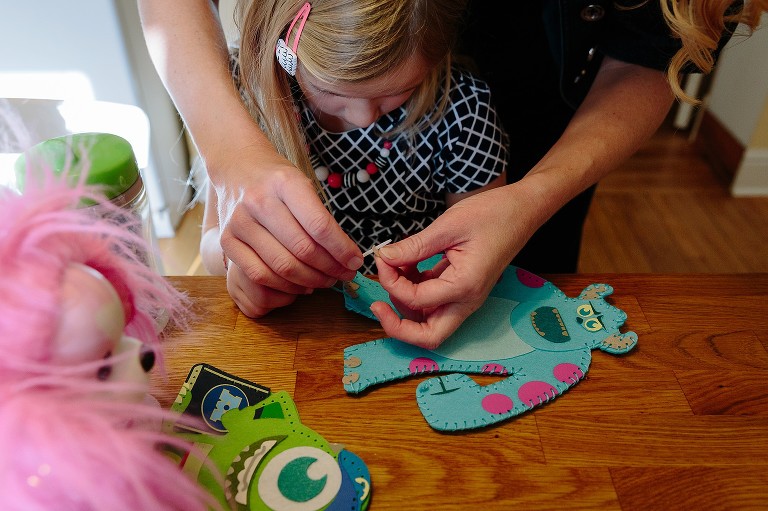 Mom helps daughter with sewing craft.