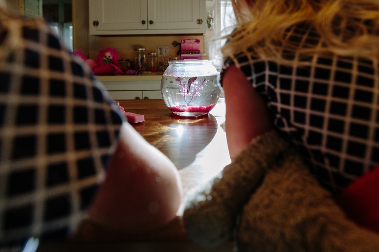 Girls frame their fish bowl with fish swimming in it. 