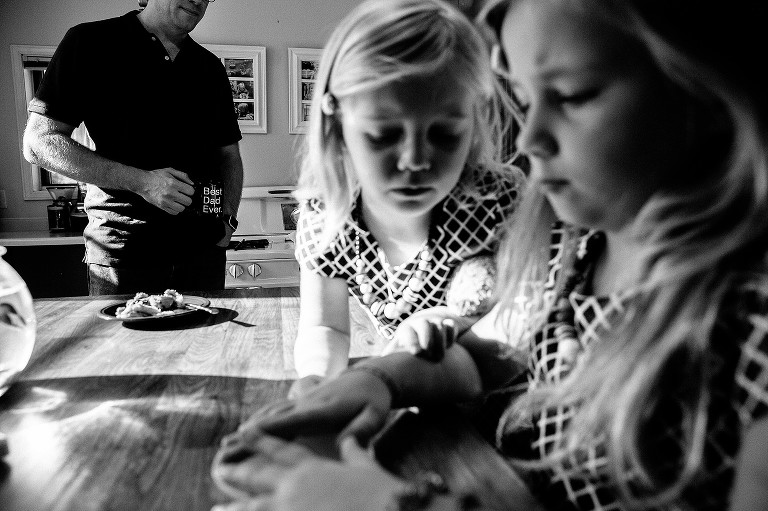 Dad holds Best Dad Ever mug while two sister make cake 