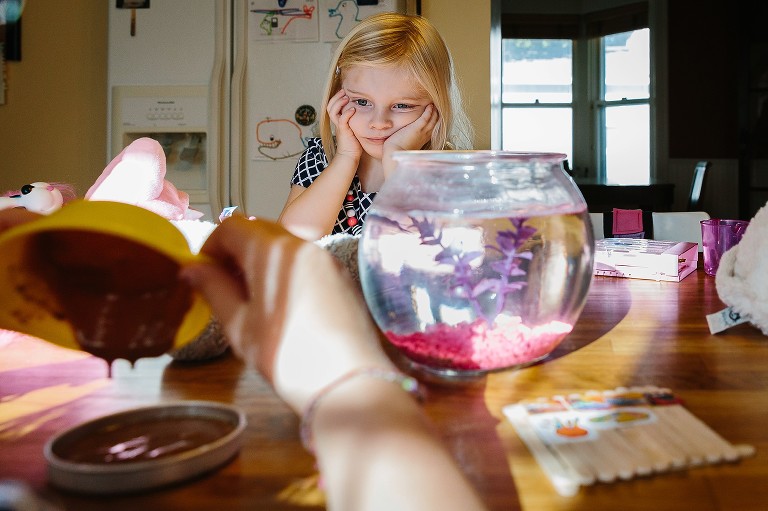 Girl watches sadly as sister puts batter in pan.