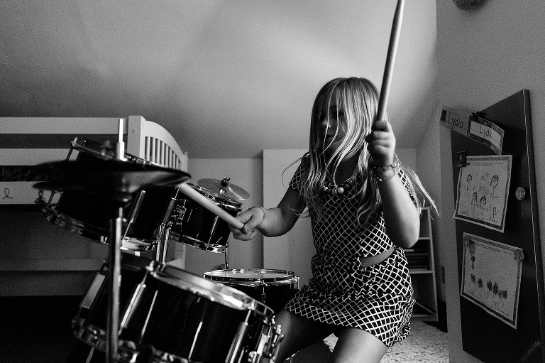 Girl plays drums while sister dances 