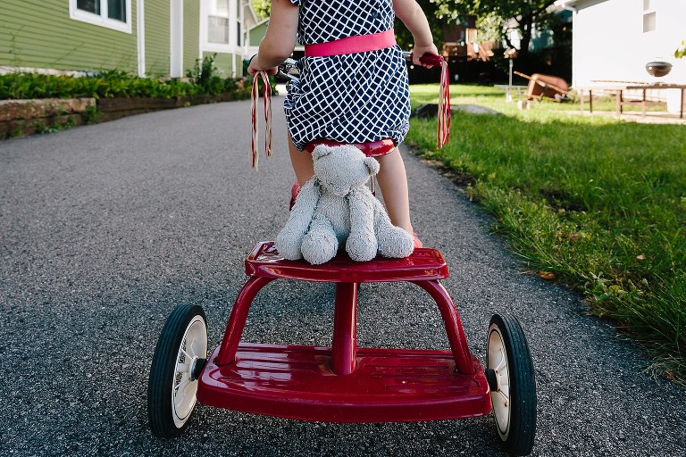 Girl brings teddy bear on a tricycle ride 