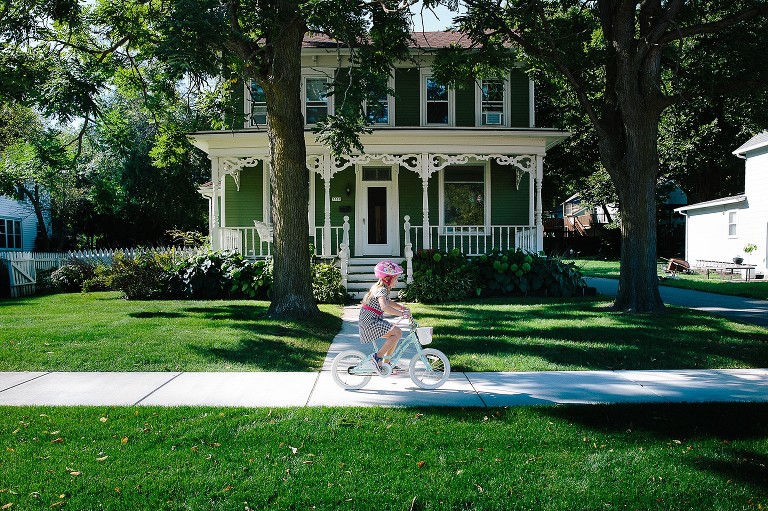 Girl rides bike  in front of house 
