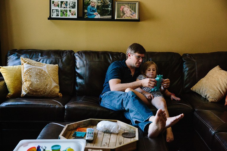 Dad and daughter sit on couch and look at sewing craft 
