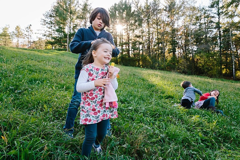 older boy plays wiht younger sister's hair while young boy and older sister play in the background 