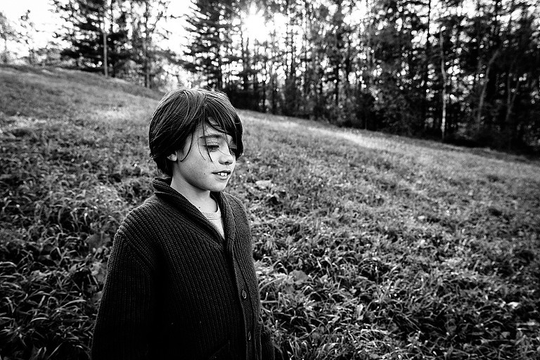black and white photo of a boy on a hill. 