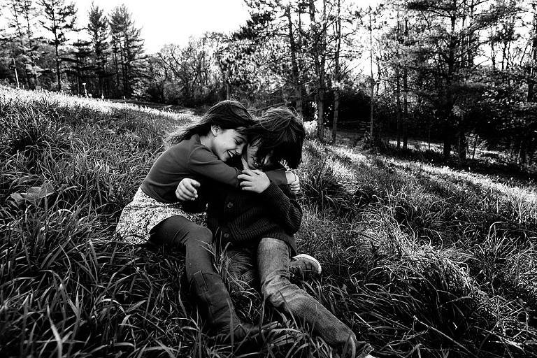 Brother and sister hug in the wind on a hill. 