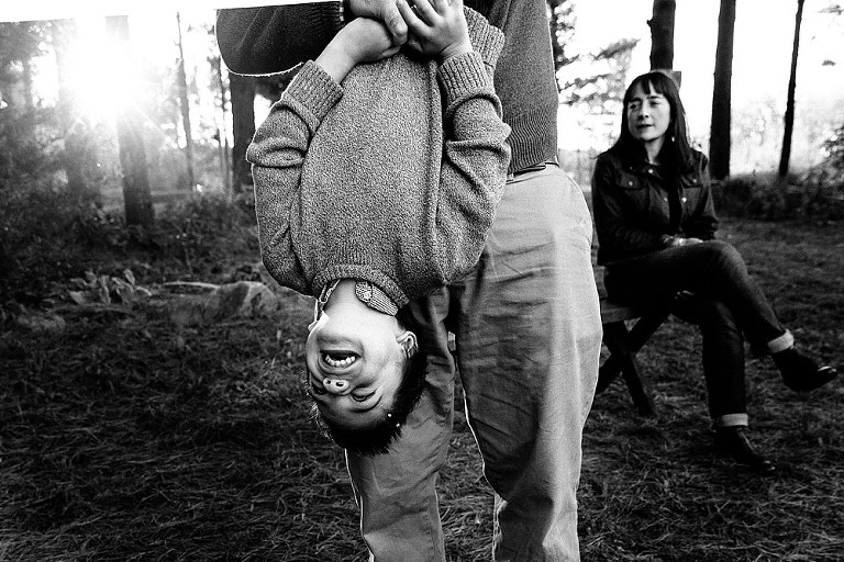 dad holds son upside down in the sun