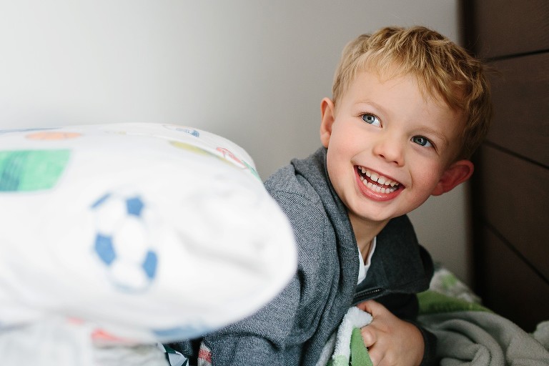 Young boy plays and laughs in his bed