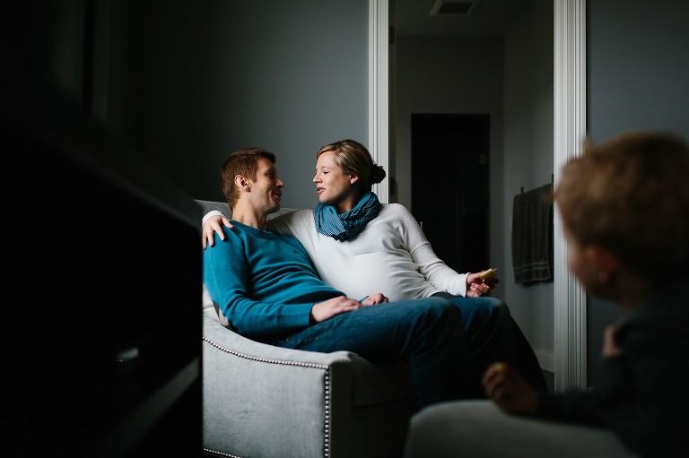 Father and pregnant mother sit in chair together