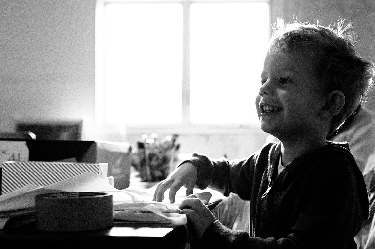 Black and white. Young boy smiles while coloring.
