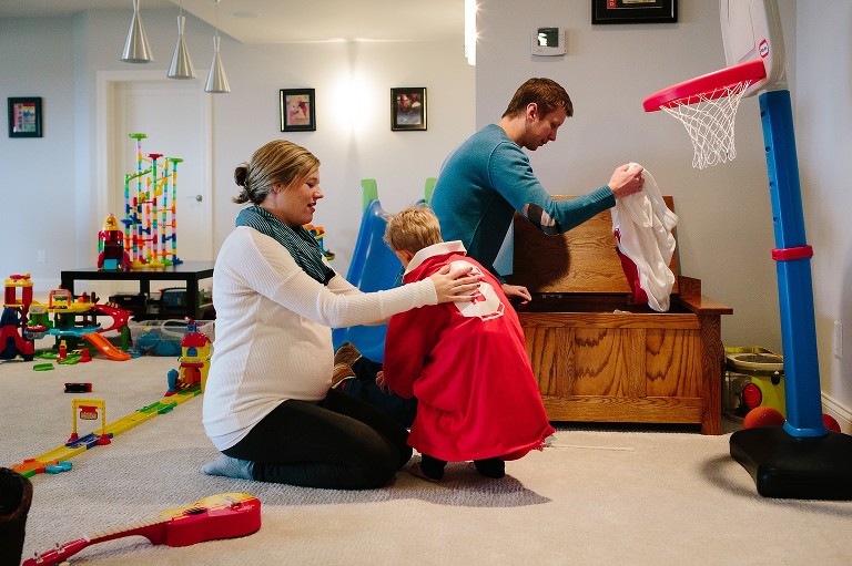 Mother helps son put on fathers old soccer jerseys in playroom.
