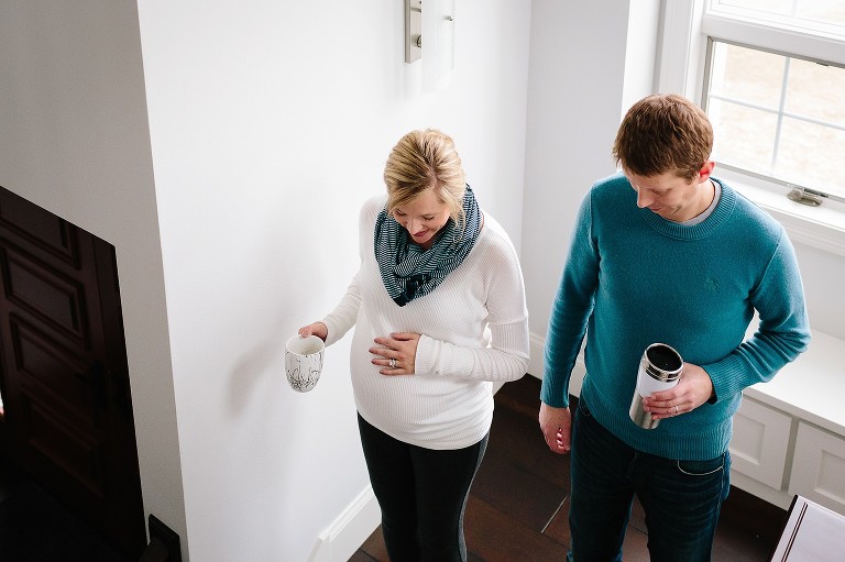 Pregnant mother and father walk up stairs together, both holding cups of coffee.