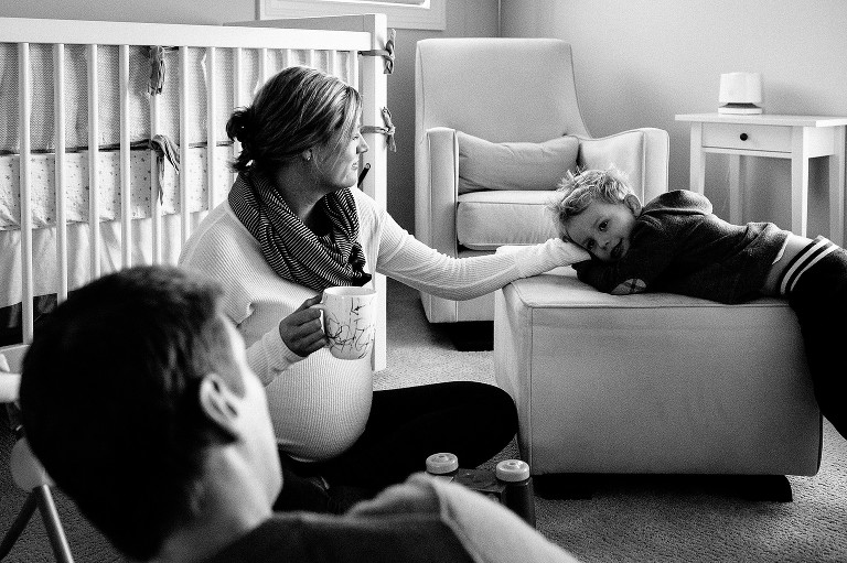 Black and white. Father, pregnant mother and son sit together in the baby's nursery.