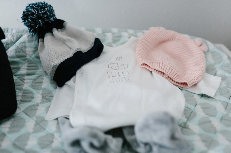 Baby onesie laying with girl and boy hat