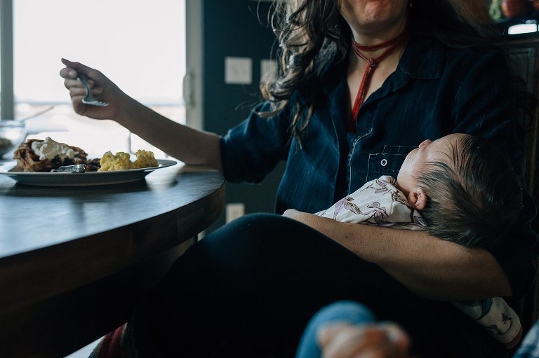 Mother eats breakfast holding newborn 