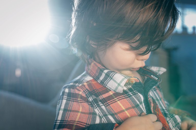 boy buttons flannel shirt in sun