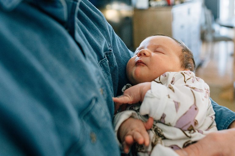 Newborn daughter sleeps in dad's arms 