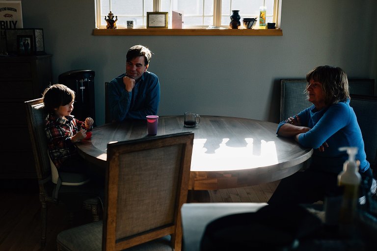 Young boy, Dad, and Grandma sit at kitchen table to talk and have snack 