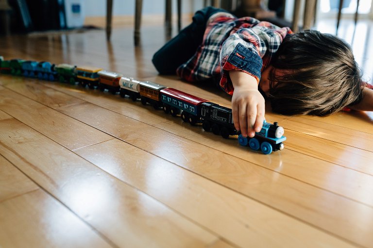 Preschooler plays with long train on the floor 
