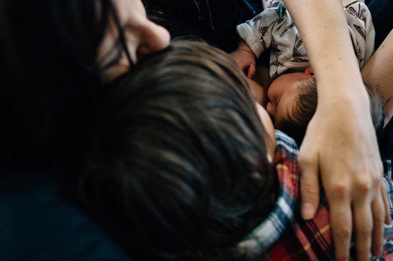Mother nurses newborn and holds preschool boy