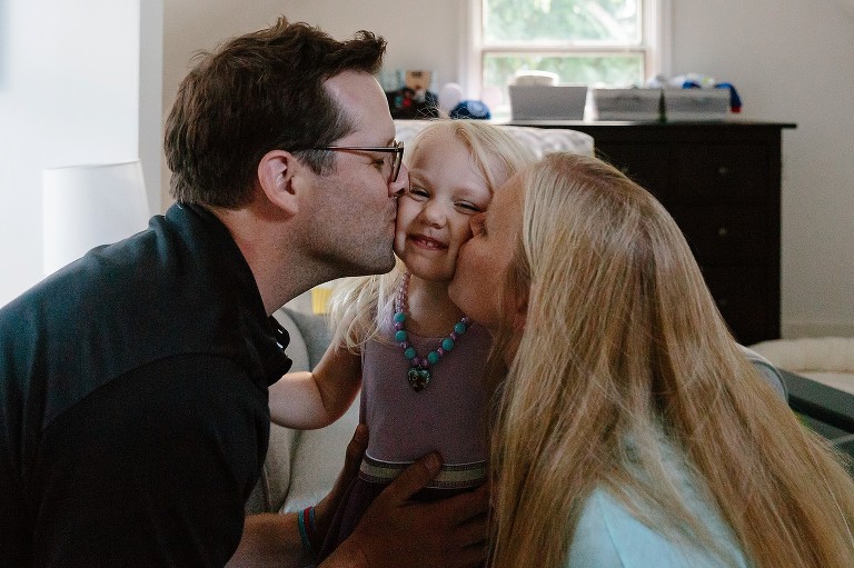 Dad and Mom kiss daughter's opposite cheeks at same time