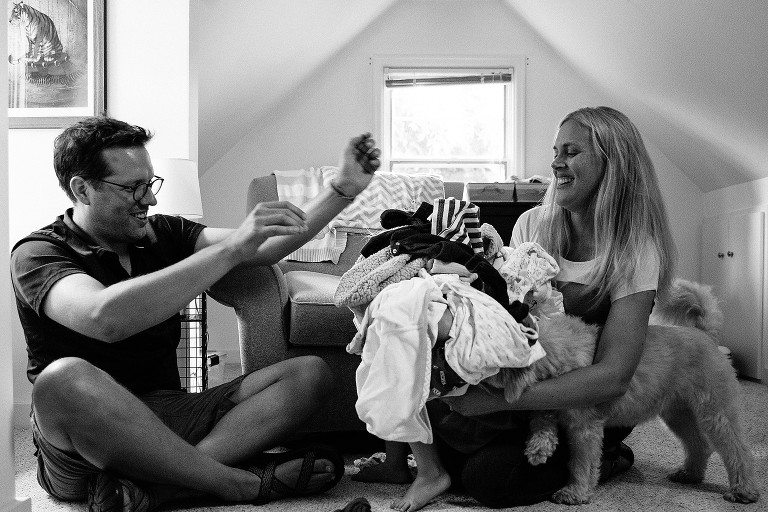 Dad and mom playfully dump clean laundry on preschool daughter and dog 