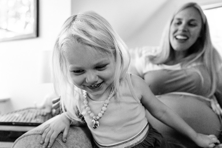 Smiling girl jumps off Mom's lap 