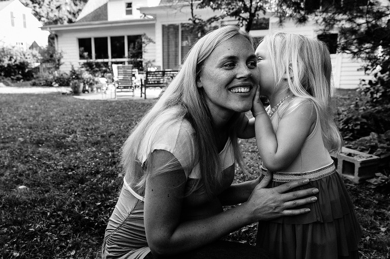 black and white. Preschool girl whispers a secret to smiling mom